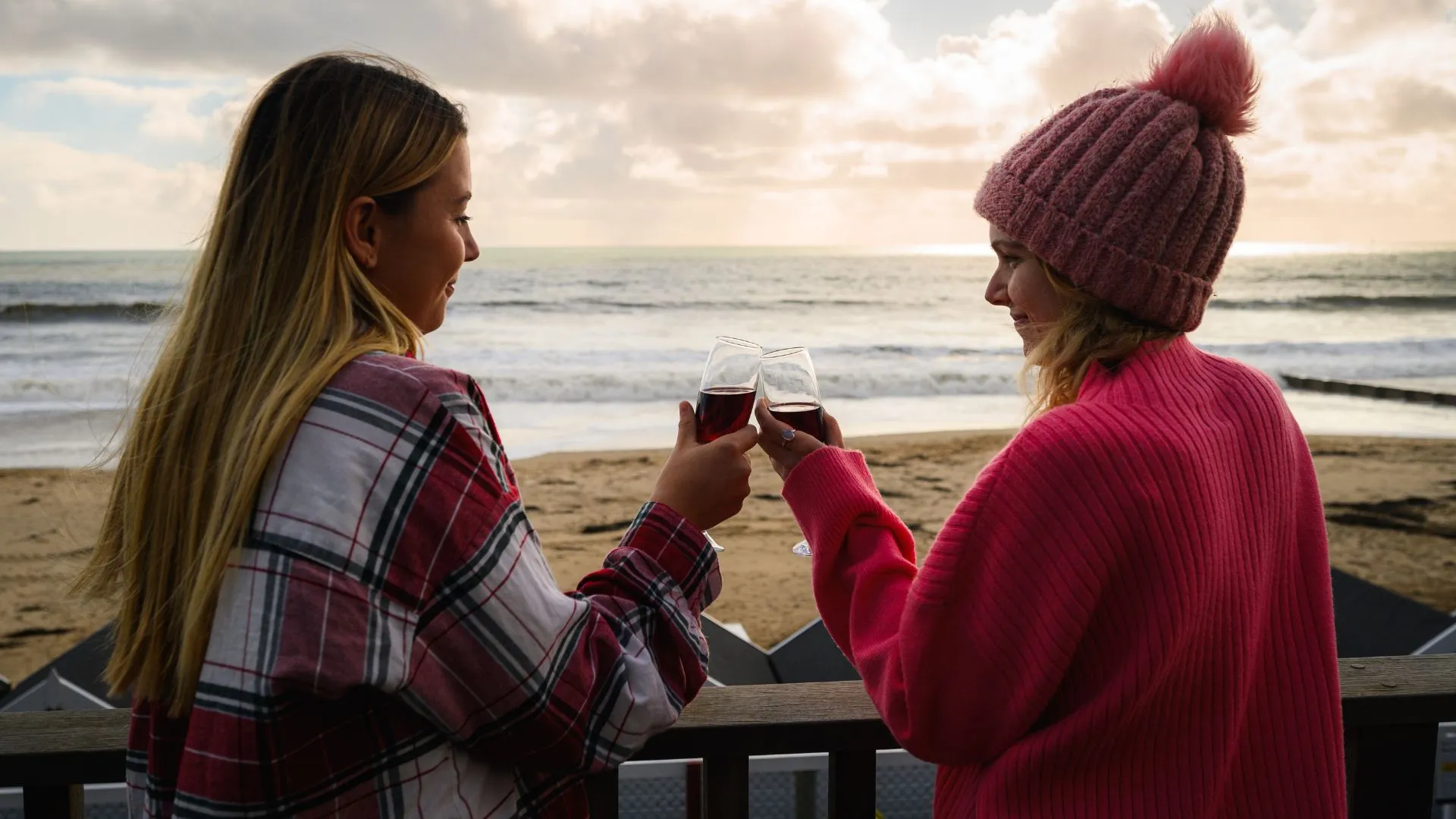 Two women holding wine glasses on terrace while taking in the beautiful view of the lodge