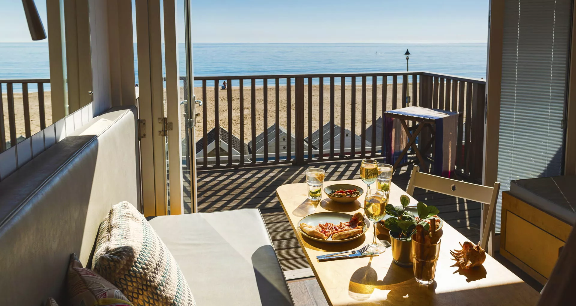 Pizza and wine on the dining table with doors opening up for the sea views