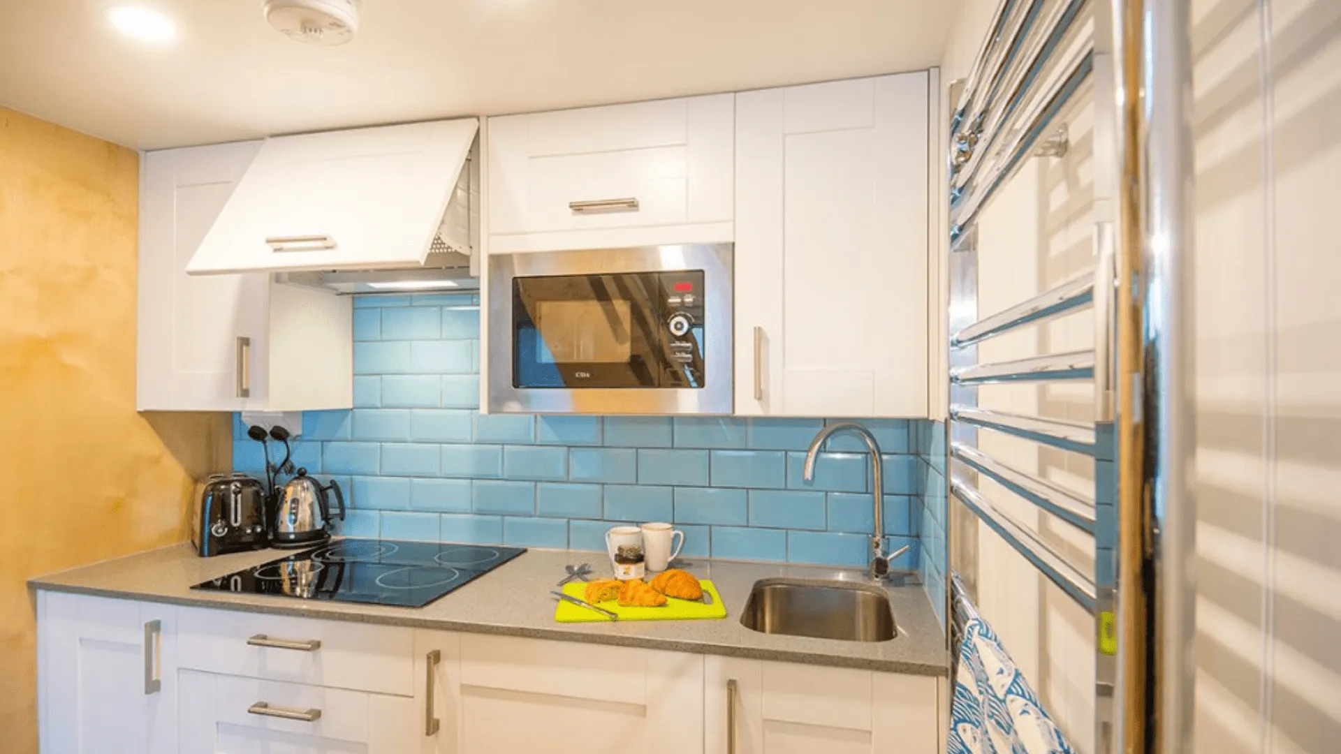 Kitchen with white cabinets and blue tiles inside Beach Lodges