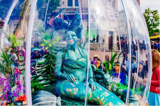 Mermaid art show inside a dome with people take photos around her