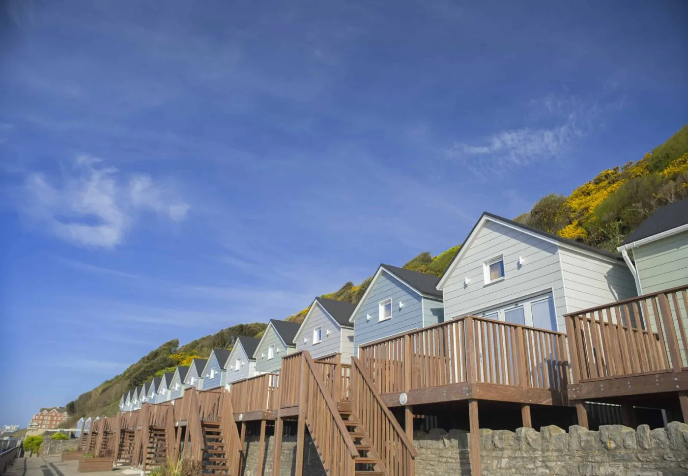 Row of self catering Beach Lodges with steps and decking on a bright, blue sunny day