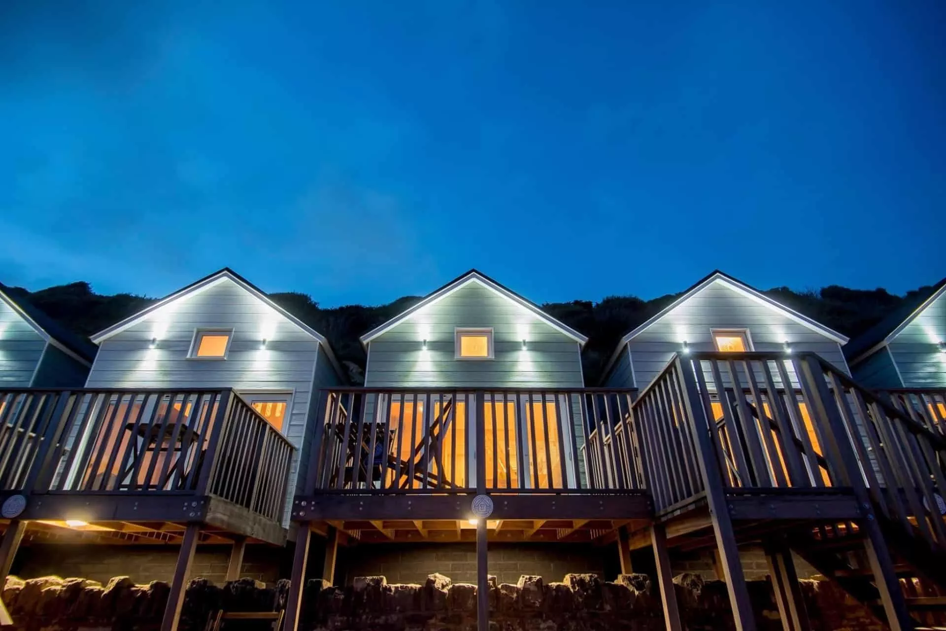 Three beach lodges lit up at night taken from the beach