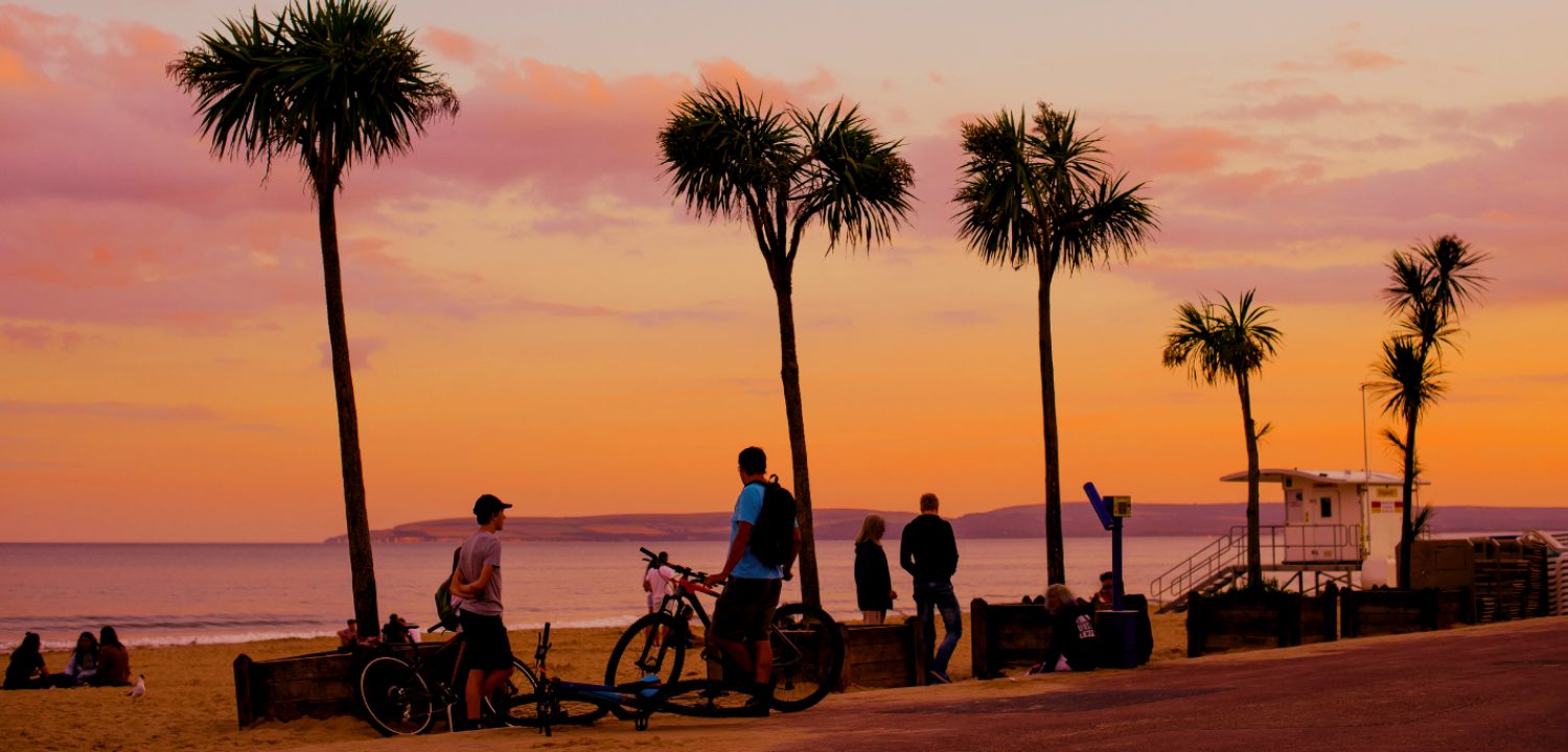 People walking and cycling at the seafront at sunset