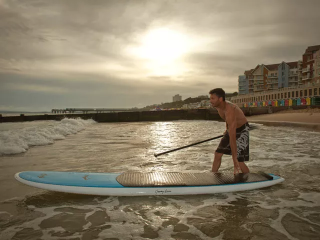 Man pushes his paddle board into the sea